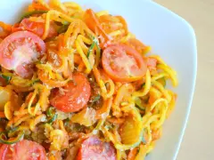 Kolorowe spaghetti z cukinii z pomidorami i startym parmezanem, zdrowe i pyszne danie.